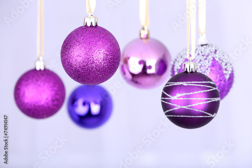 Hanging purple Christmas toys on light background