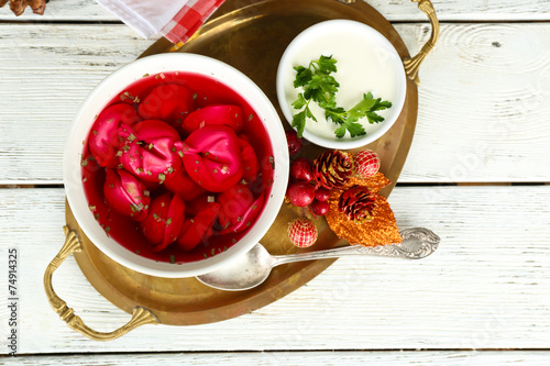 Traditional polish clear red borscht with dumplings in bowl