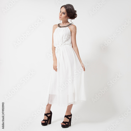 Young brunette woman in white dress. White Background.