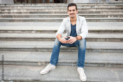 Smiling young man sitting on the stairs © bokan