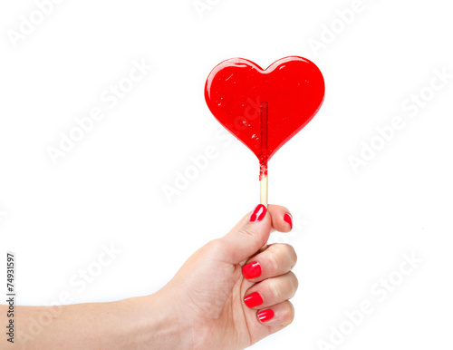 red heart shaped candy lollipop in hand