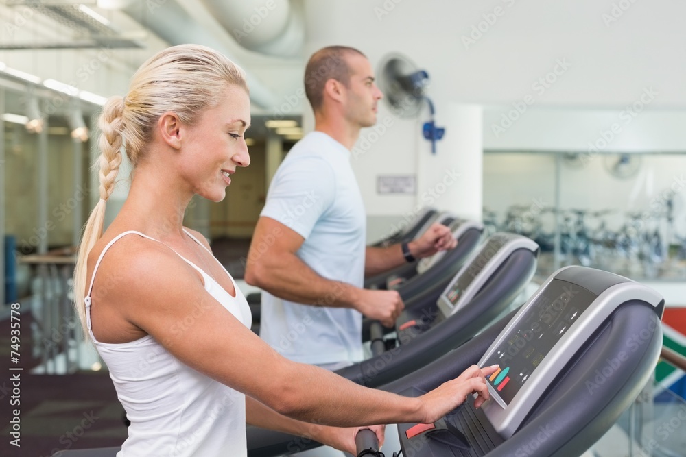 Side view mid section of couple running on treadmills at gym Side view mid section of couple running on treadmills at gym