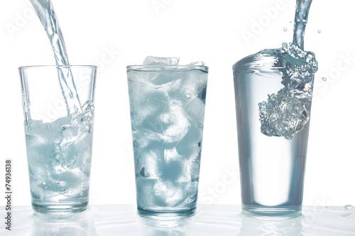 Trinkwasser aus einer Flasche in ein Glas mit Eiswürfeln gießen