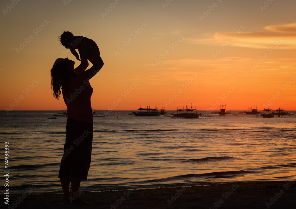 mother and daughter having fun at sunset beach