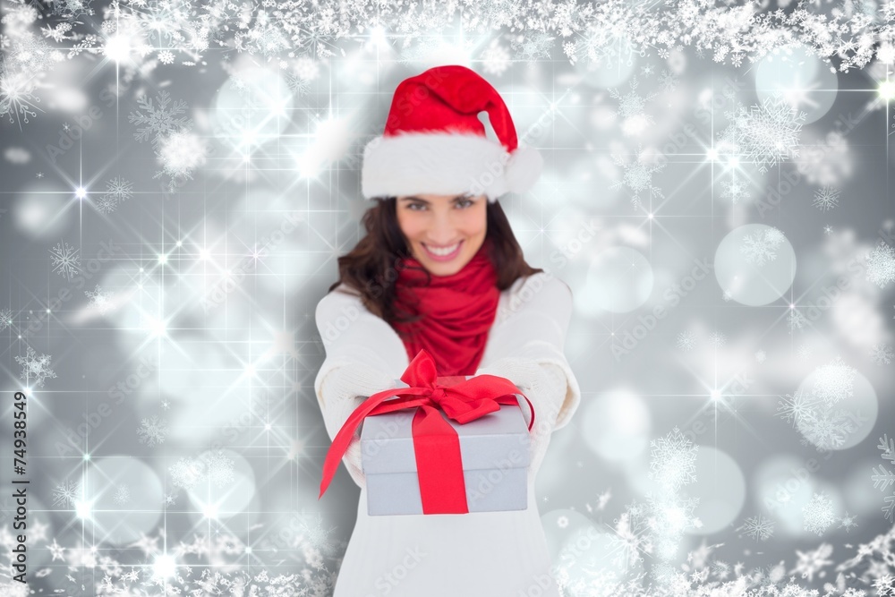 Composite image of festive brunette in santa hat giving gift Composite image of festive brunette in santa hat giving gift