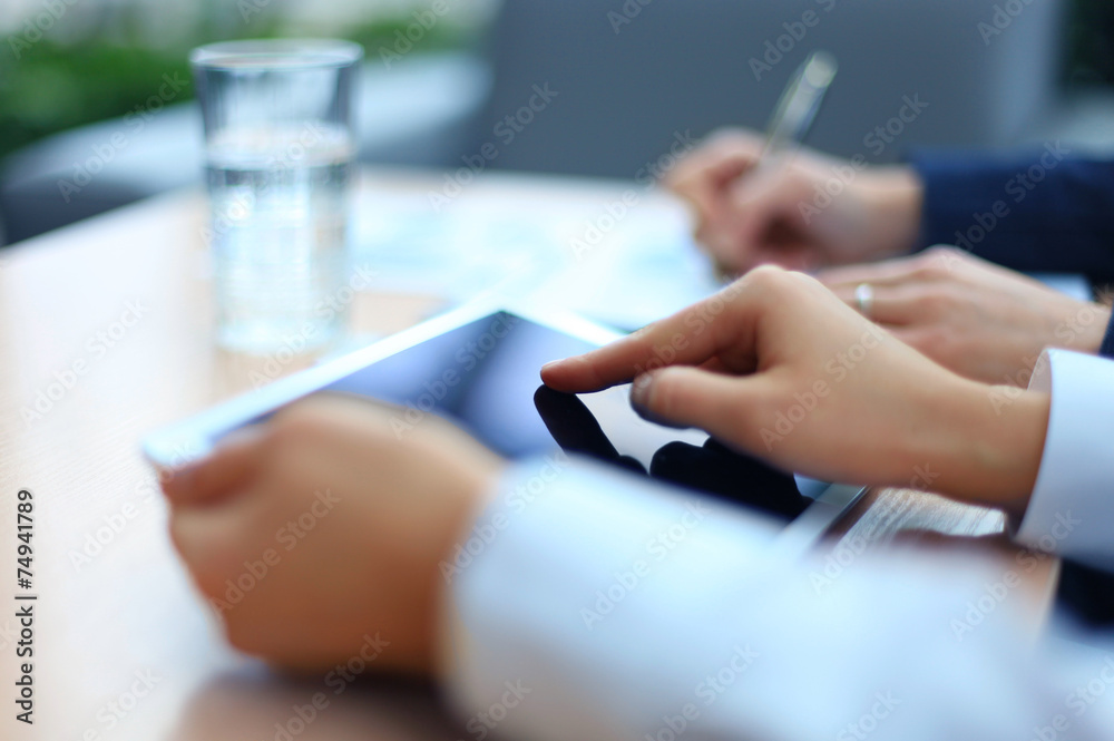 Image of two young businessmen using touchpad at meeting Image of two young businessmen using touchpad at meeting