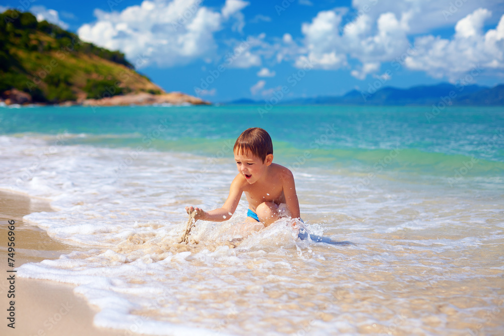 young boy, kid playing with sand in surf young boy, kid playing with sand in surf