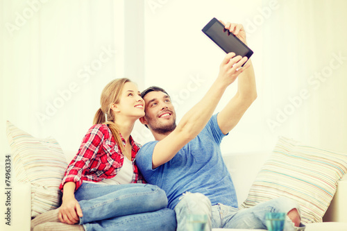 smiling couple with tablet pc computer at home