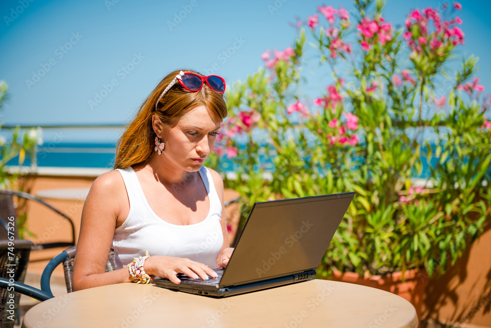 girl with laptop on the terrace of summer cafe