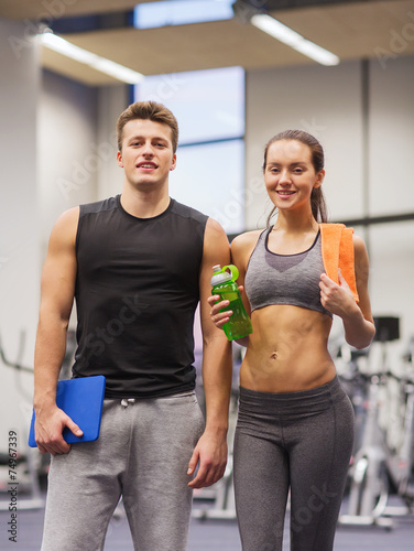 happy couple in gym with water and tablet pc