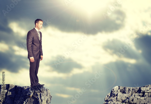 Businessman standing on the edge of rock gap