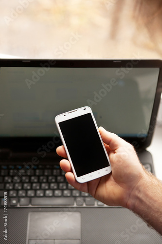 Man using smartphone, close-up, notebook on the background