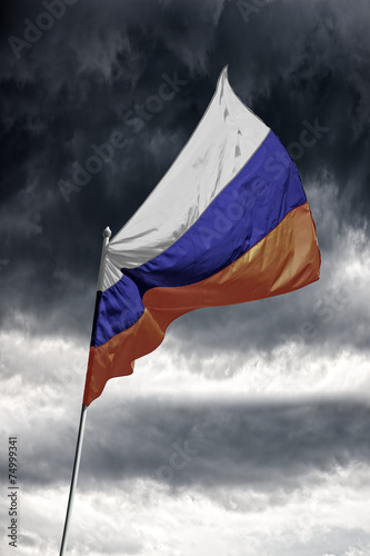 Russian flag on a dark cloudy dramatic sky.