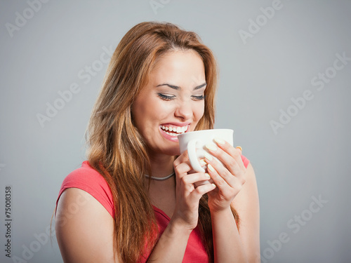 Studio shot of smiling young woman drinking coffee or tea