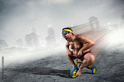 Adult crazy man cycling on child's bicycle photo