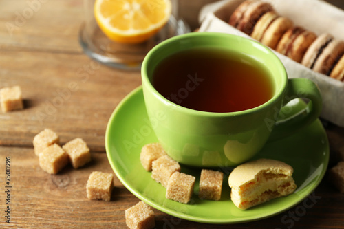 Colorful macaroons with cup of tea on wooden background