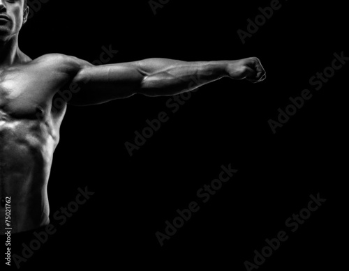 Handsome muscular bodybuilder posing and keeping arms outstretch