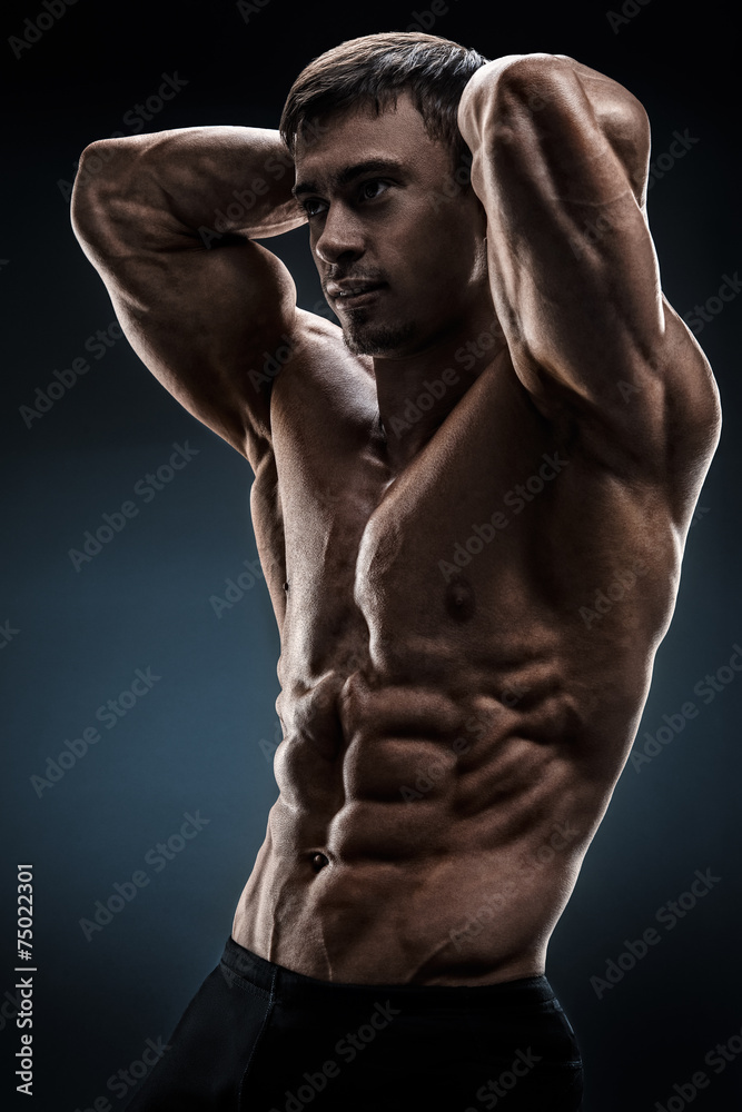 Handsome muscular bodybuilder posing over black background