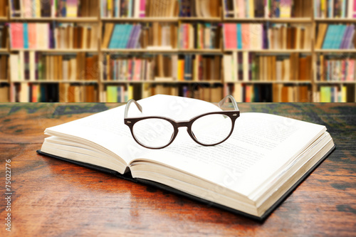 book and glasses against library background