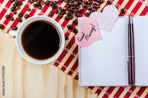 open notepad with cup of coffee on striped napkin