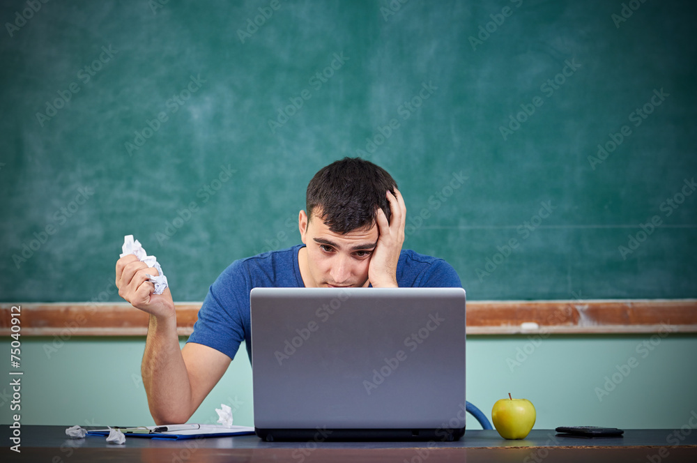 Stressed overworked man studying in front of notebook. Stressed overworked man studying in front of notebook.