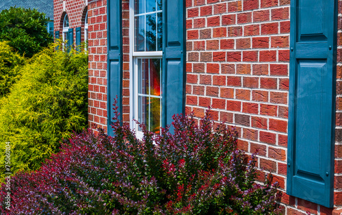Fotografía Bushes and front of brick house with blue shutters