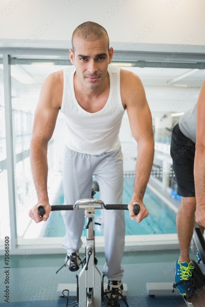Handsome man working out on exercise bike at gym