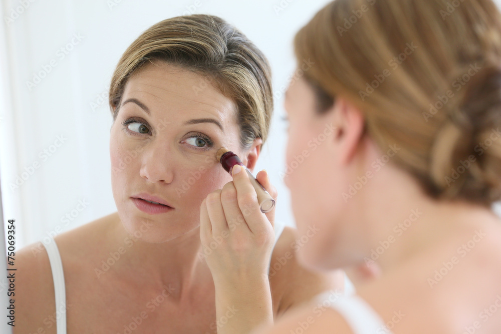 Beautiful blond woman applying concealer around eyes Beautiful blond woman applying concealer around eyes