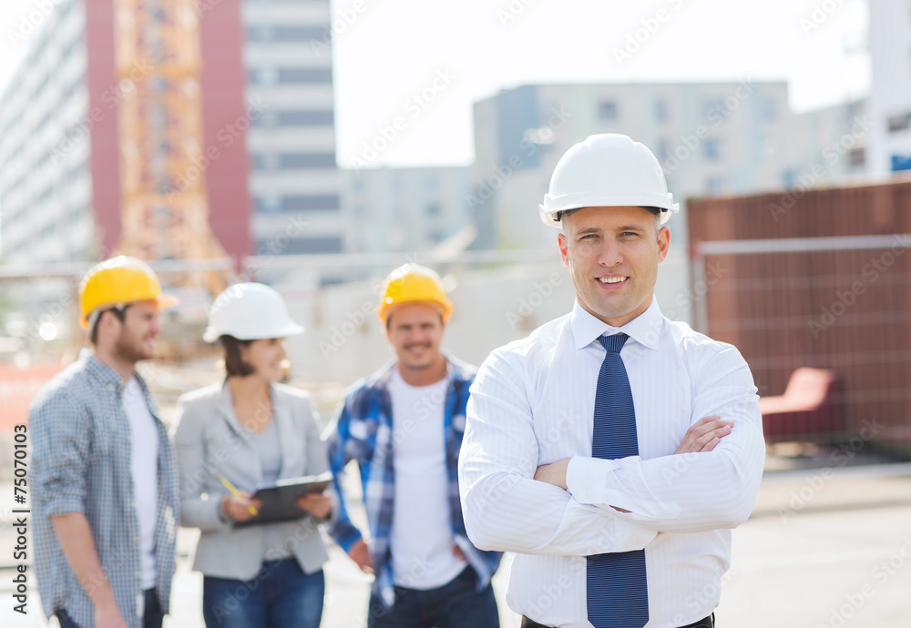 group of smiling builders in hardhats outdoors group of smiling builders in hardhats outdoors
