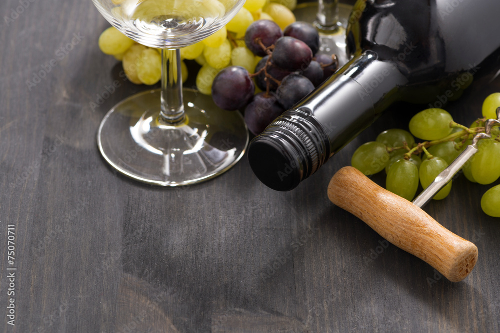 Obraz premium bottle of red wine and grapes on a wooden background, close-up