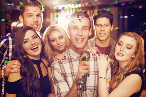 Composite image of happy friends singing karaoke together