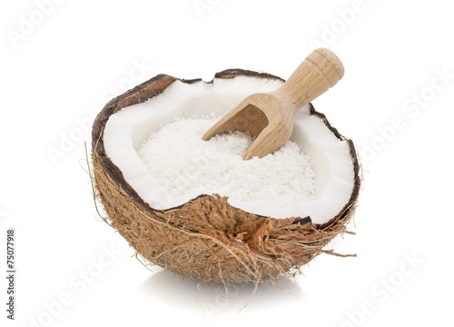 A coconut with desiccated coconut and scoop on white background