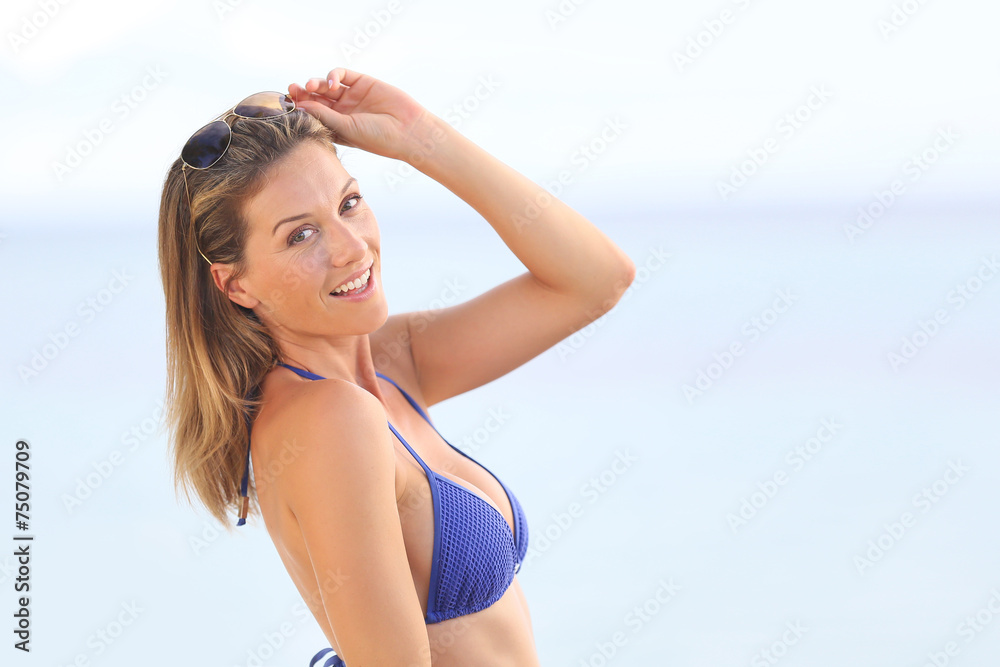 Blond woman in bikini with eyeglasses posing by the beach Blond woman in bikini with eyeglasses posing by the beach