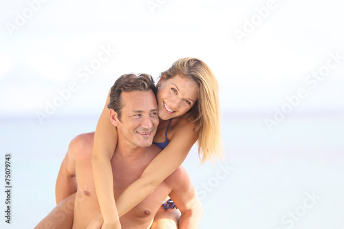 Cheerful 40-year-old man giving piggyback ride to woman © goodluz