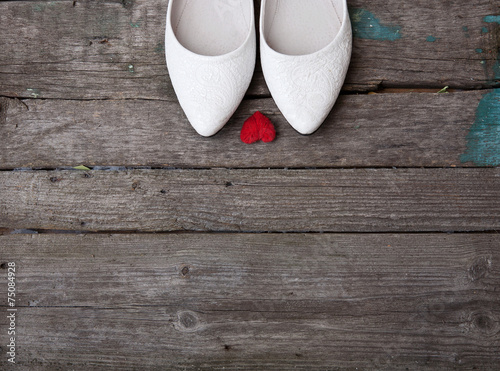 wedding shoes and red heart on wood background
