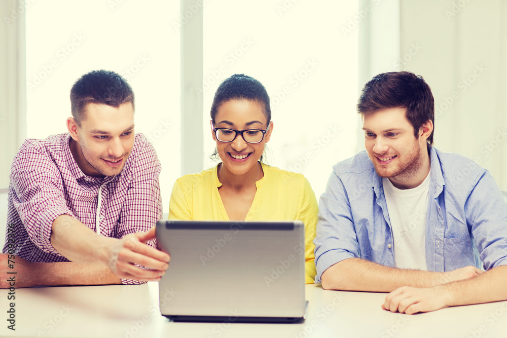 three smiling colleagues with laptop in office three smiling colleagues with laptop in office