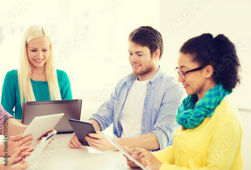 smiling team with table pc and laptop in office