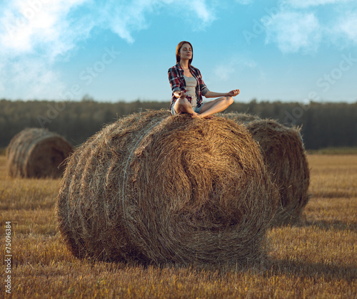 Canvas-taulu Young woman meditating on haystack