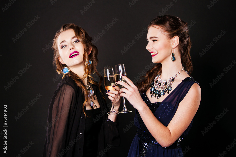 Two beautiful women in black cocktail dresses with glasses of