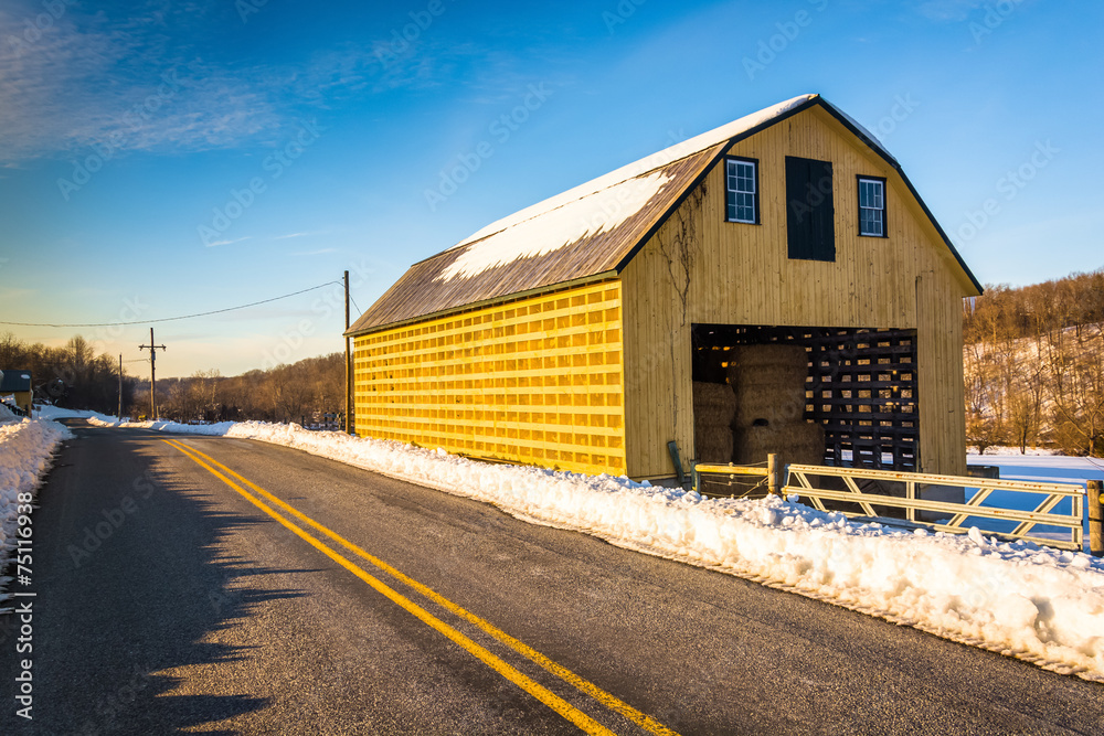 Yellow barn and a snow covered field along a country road in Yor