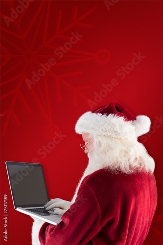 Composite image of santa claus uses a laptop