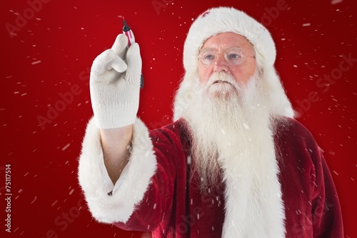 Composite image of santa writes something with a pen
