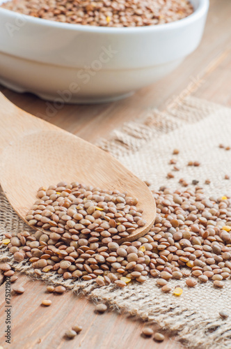 Organic lentils with wooden false on burlap background
