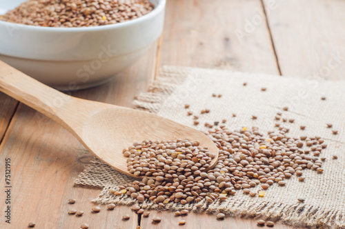 Organic lentils with wooden false on burlap background