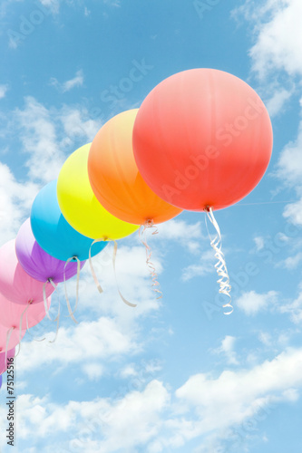 Chain of colored balloons into the blue sky among the clouds