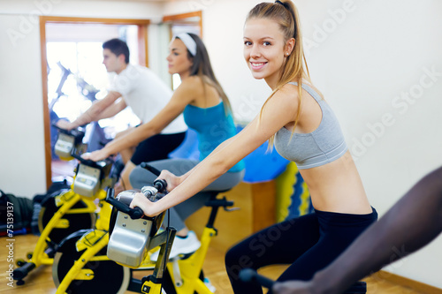 Young people with fitness bycicles in the gym.