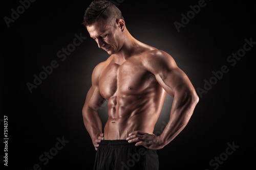 Muscular man in studio on dark background © bondarchik