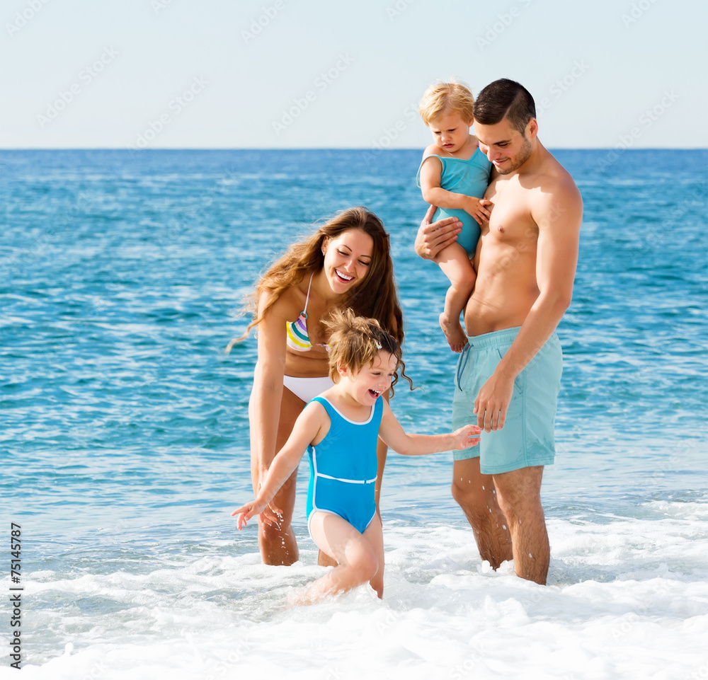 Naklejka premium Family with two kids on beach