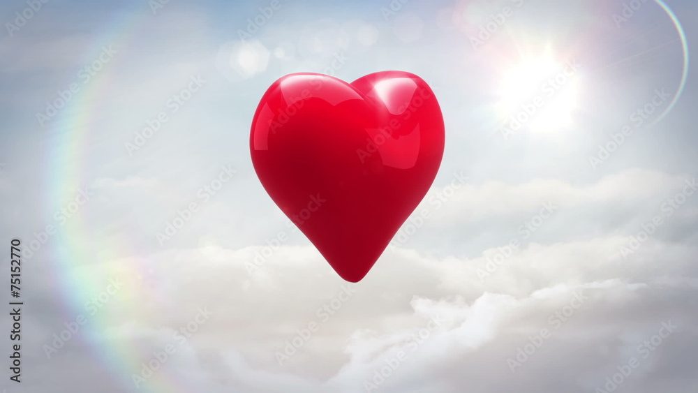 Red heart turning and exploding over blue sky