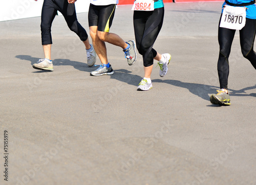 marathon athletes legs running on city road 